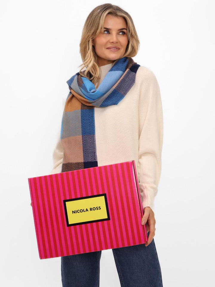 Woman holding a pink striped bag with 'Nicola Ross' branding, wearing a colorful scarf.