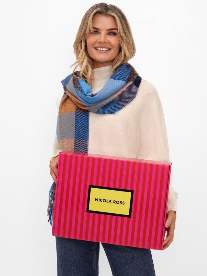Woman holding a pink striped box with 'Nicola Ross' branding, wearing a colorful scarf.