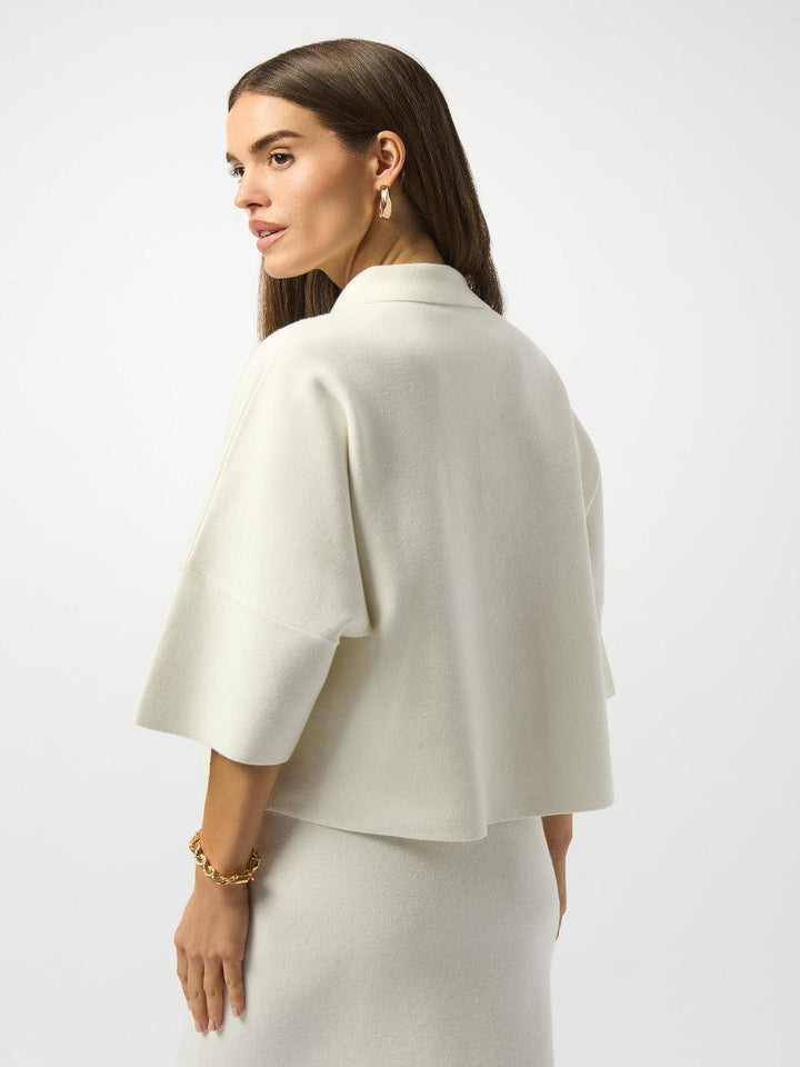 Woman wearing a white cape over a plain background