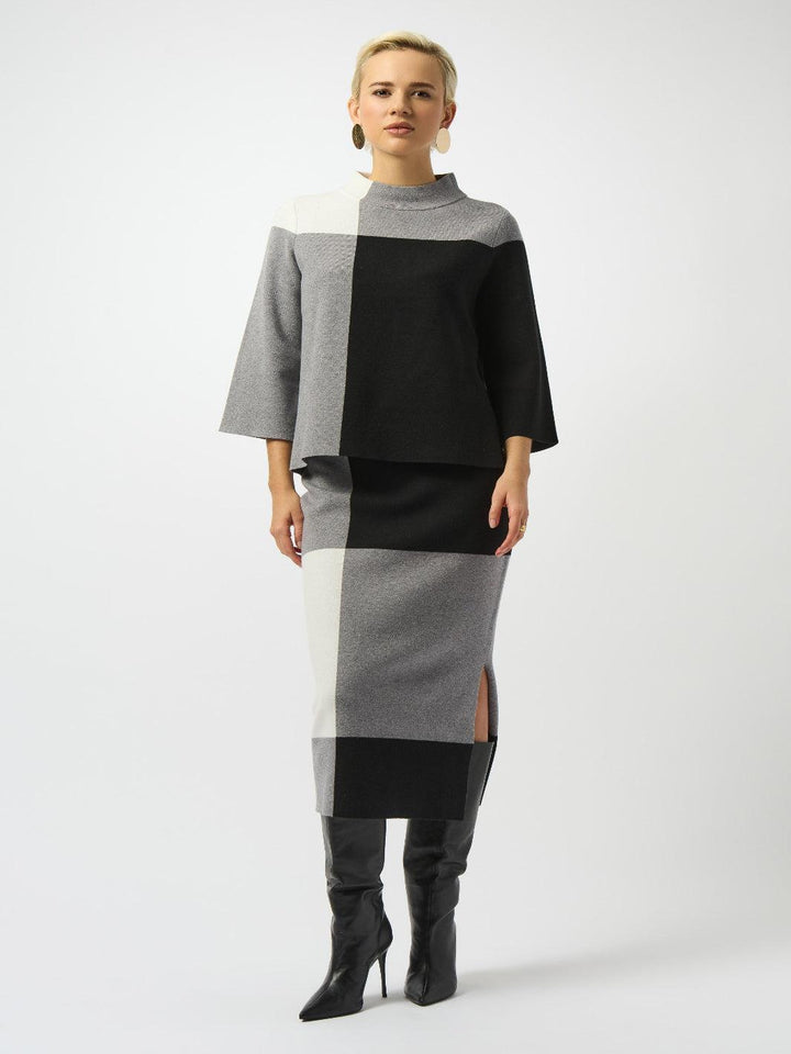 Woman wearing a black, gray, and white color-blocked outfit on a white background