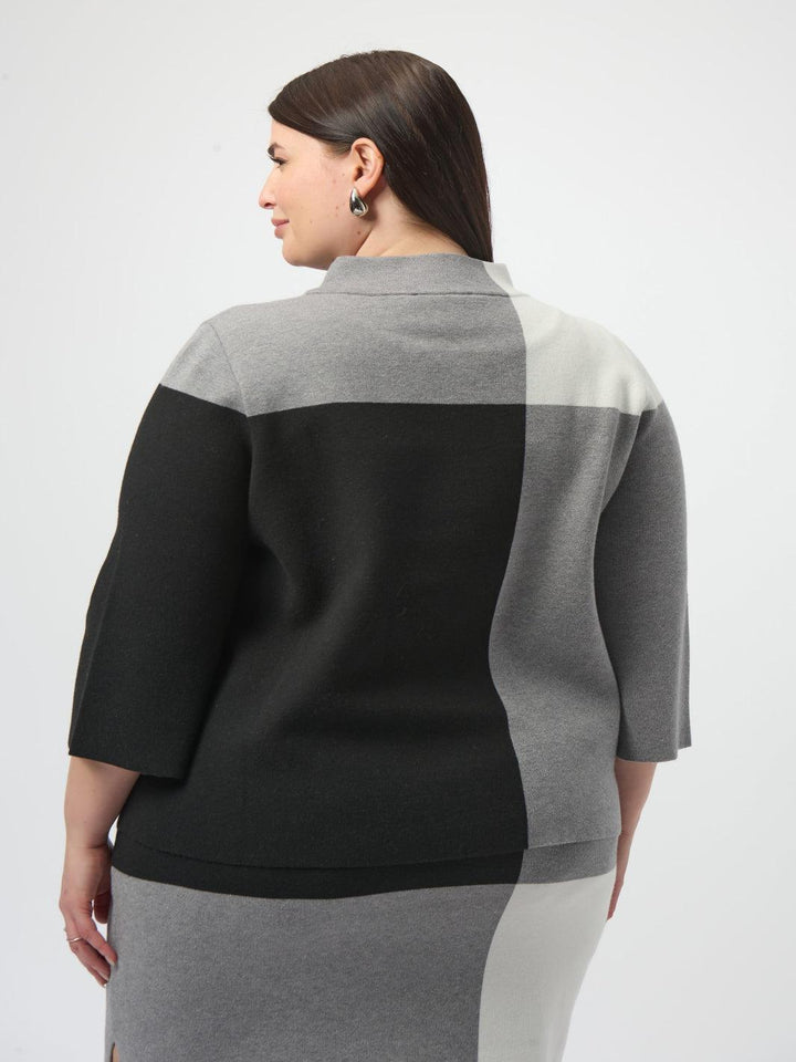 Woman wearing a black and gray color-blocked sweater on a white background
