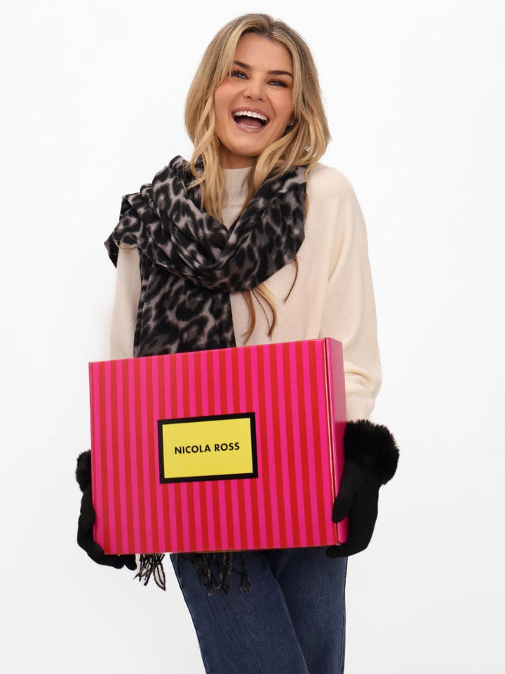 Woman holding a large pink striped gift box with 'Nicola Ross' label