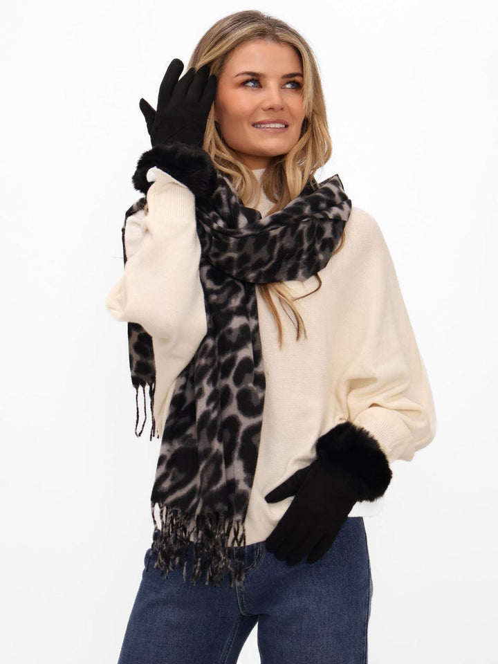 Woman wearing a leopard print scarf and black gloves on a white background