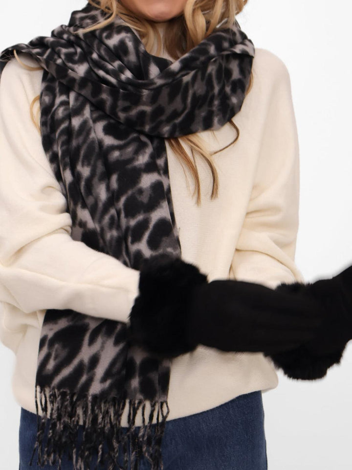 Person wearing a leopard print scarf and black gloves on a white background