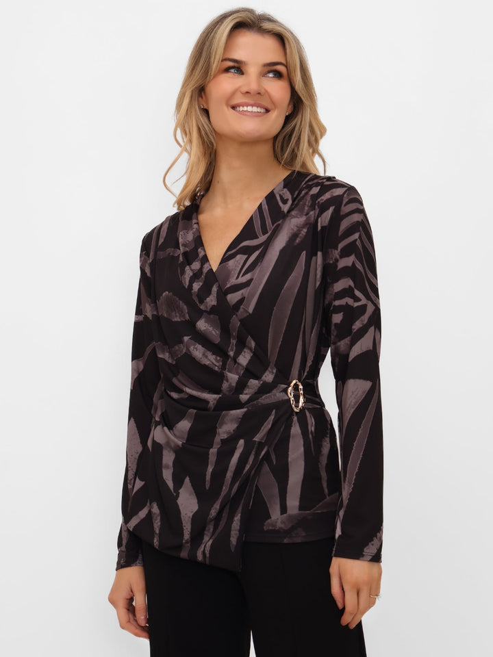 Woman wearing a patterned black and gray blouse with a belt on a white background