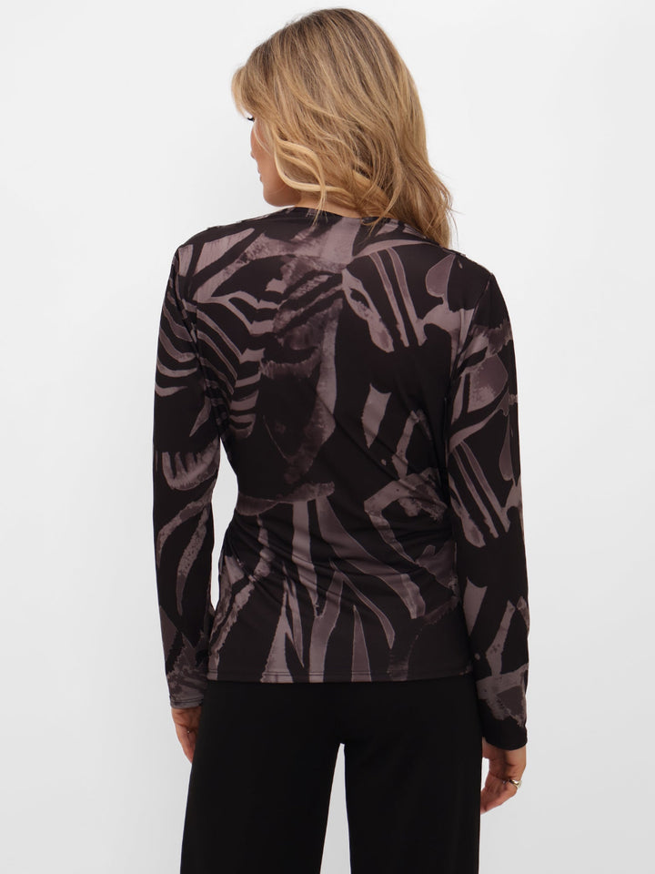 Woman wearing a black and purple patterned long-sleeve top on a white background