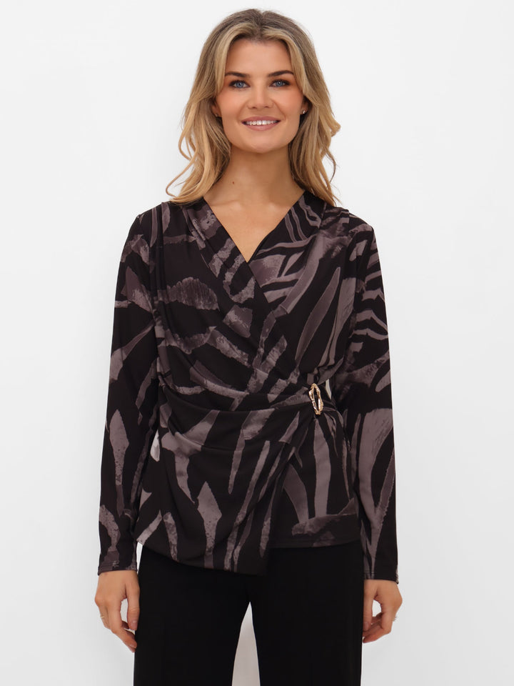 Woman wearing a patterned top with a belt on a white background