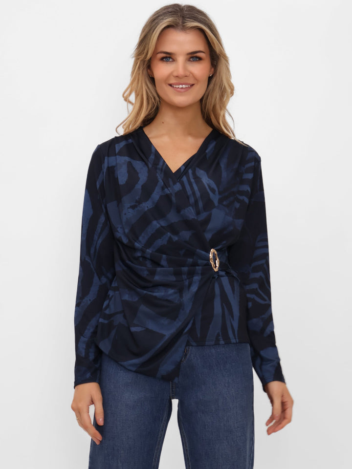 Woman wearing a navy patterned top with a belt on a white background