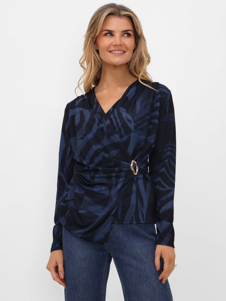 Woman wearing a navy patterned top with a belt against a white background
