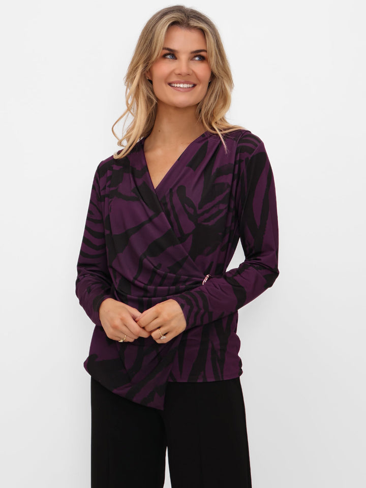 Woman wearing a purple patterned top against a white background