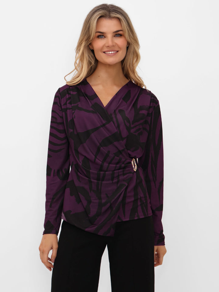Woman wearing a purple patterned top on a white background