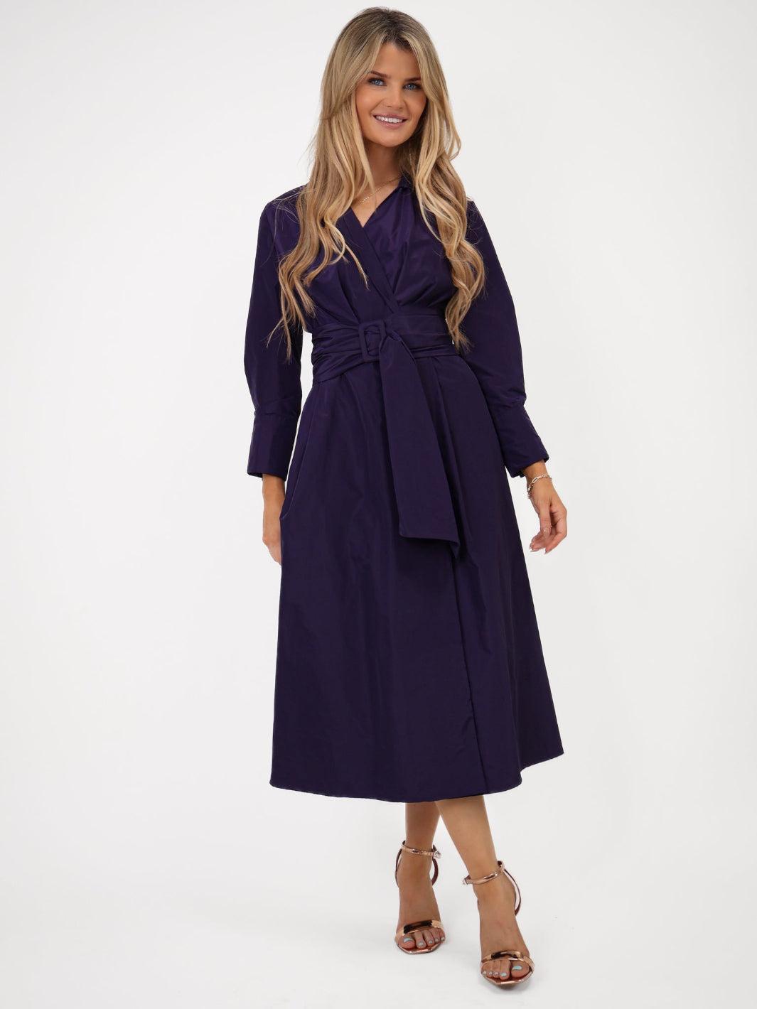 Woman wearing a purple dress with a belt on a white background