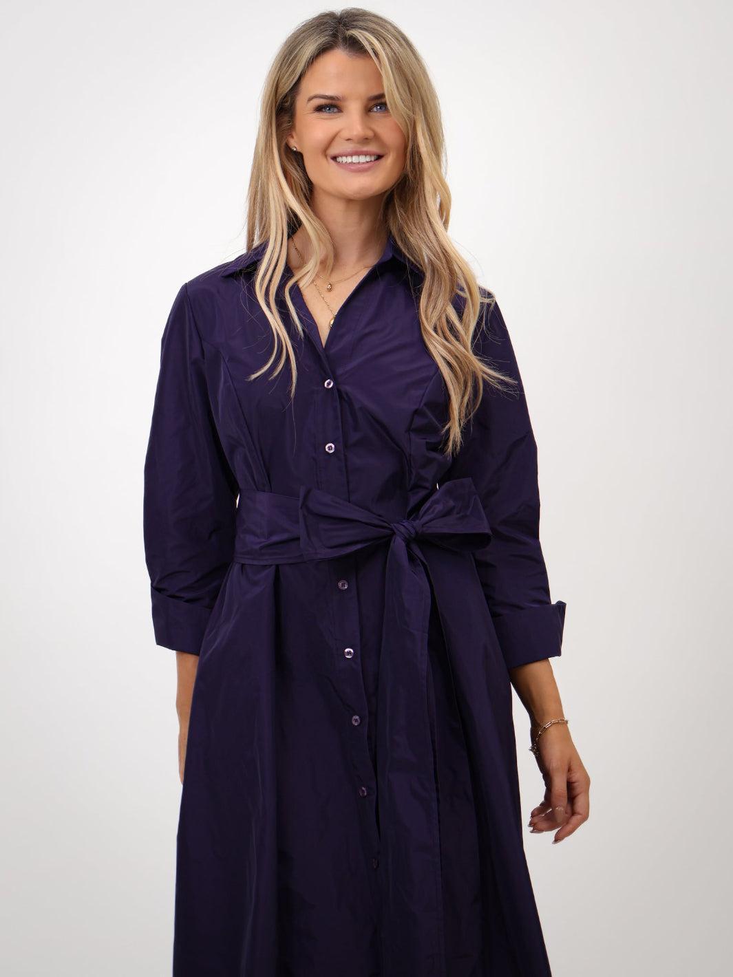 Woman wearing a purple dress with a belt on a white background