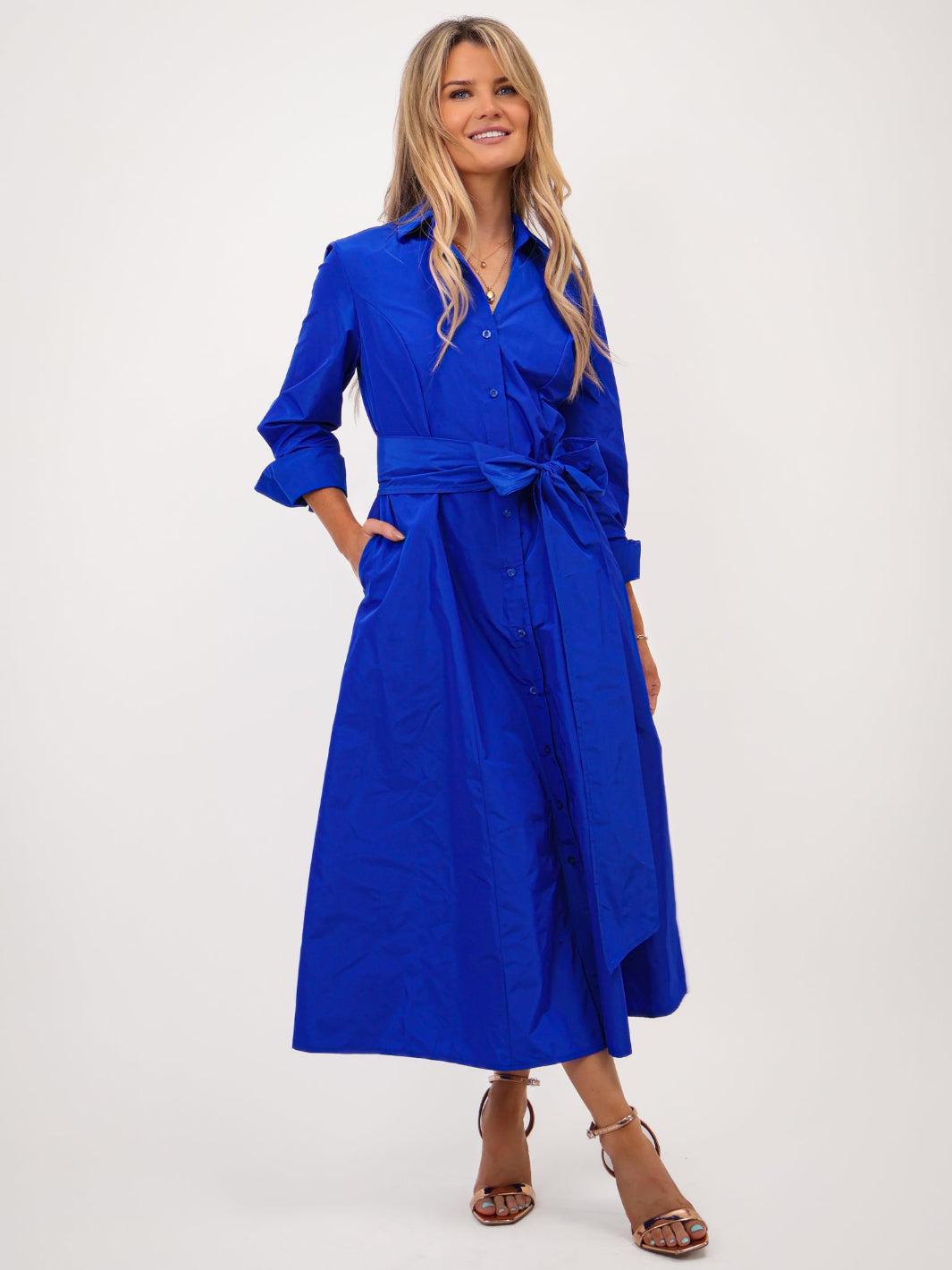 Woman wearing a blue dress with a belt on a white background