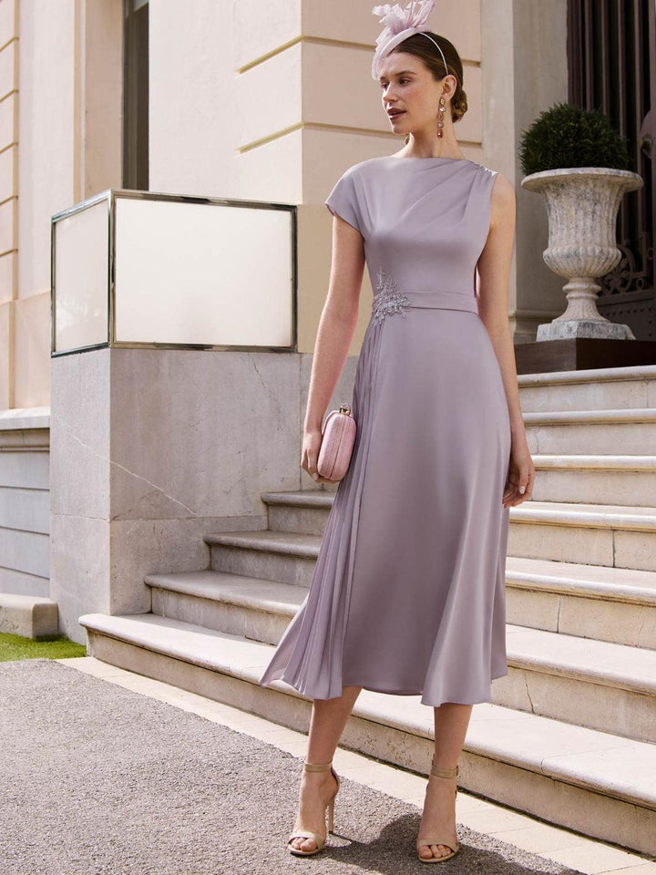 Woman in a light purple dress standing on steps outside a building