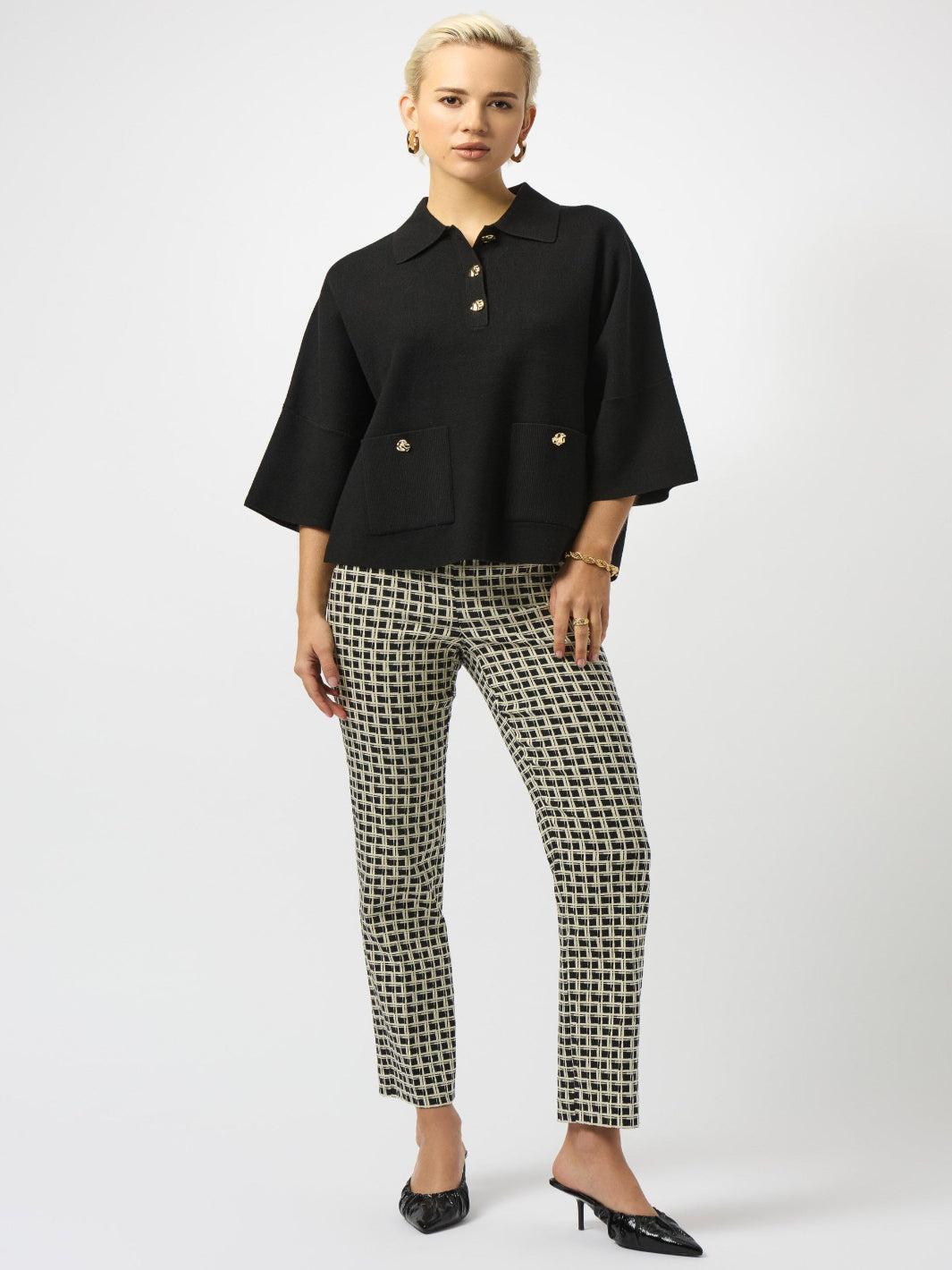 Woman wearing a black blouse with gold buttons and patterned pants on a white background