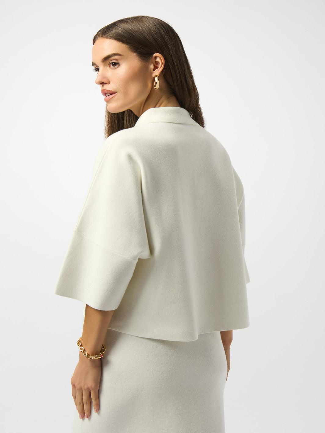 Woman wearing a white cape over a plain background