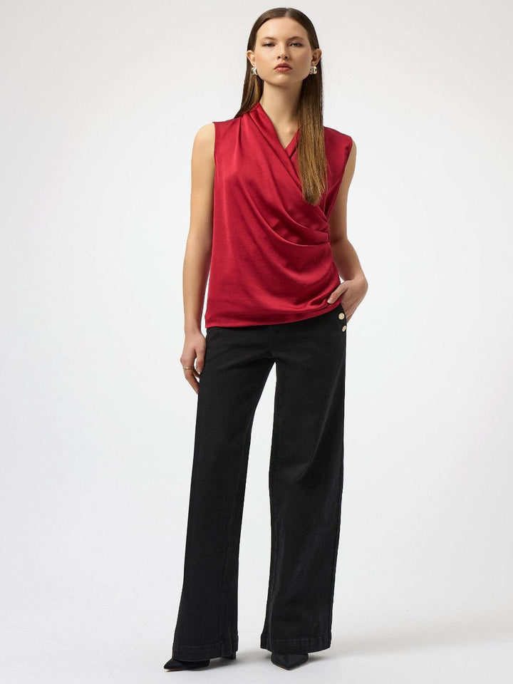 Woman wearing a red sleeveless top and black pants on a white background
