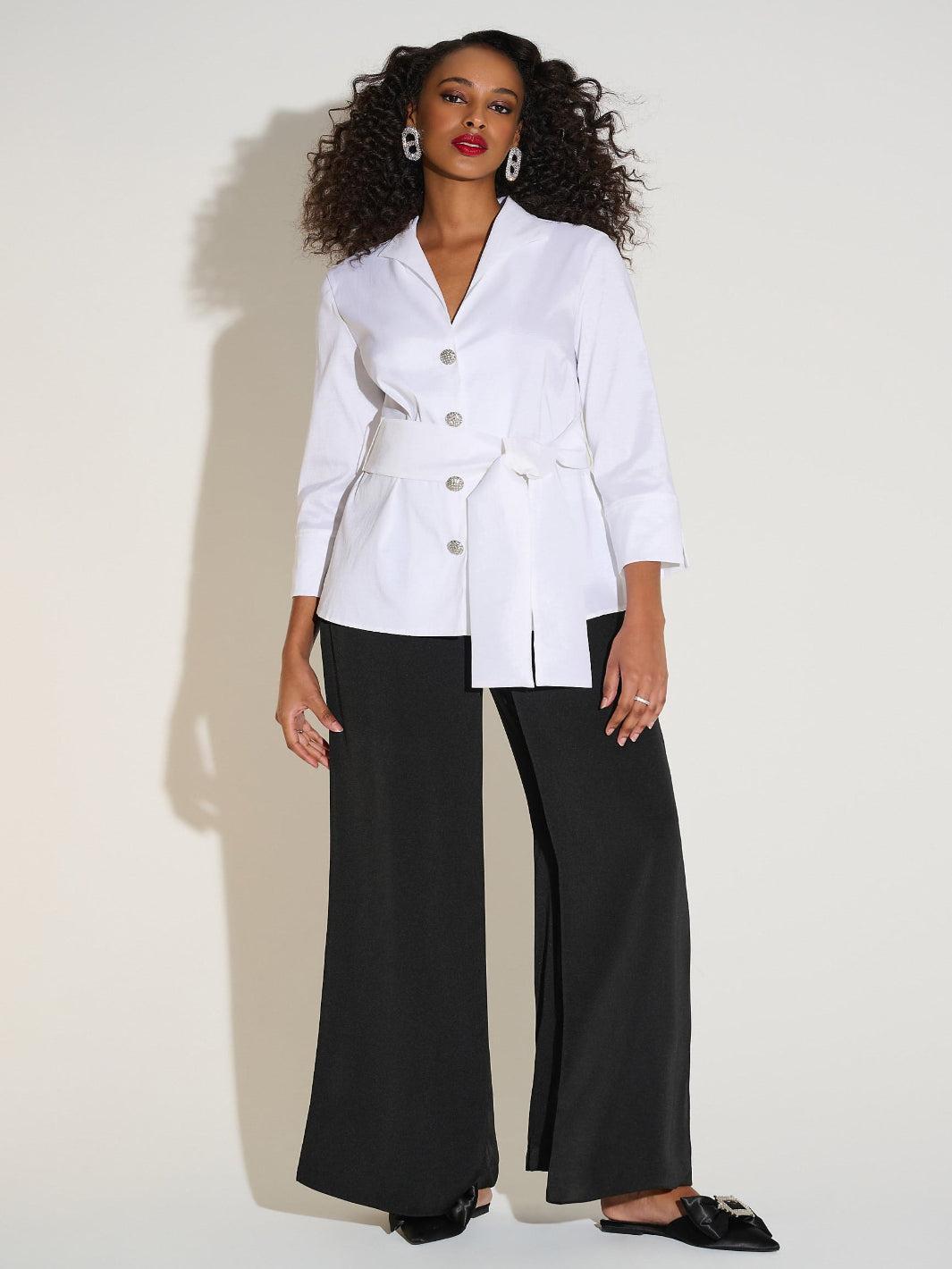 Woman wearing a white blazer and black pants on a white background