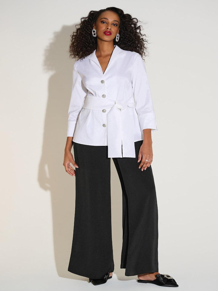 Woman wearing a white blazer and black pants on a white background