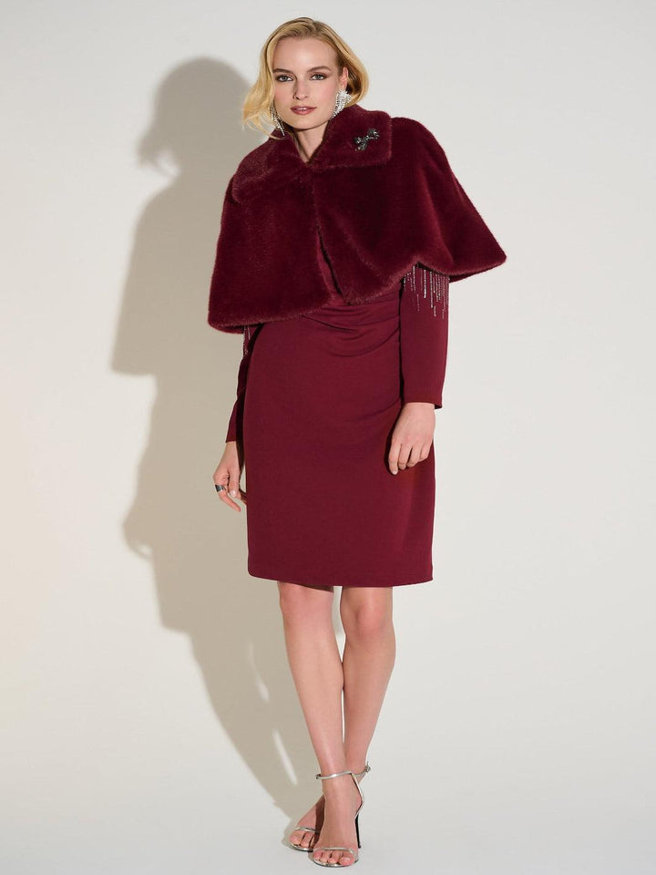 Woman wearing a burgundy dress with a matching cape against a white background