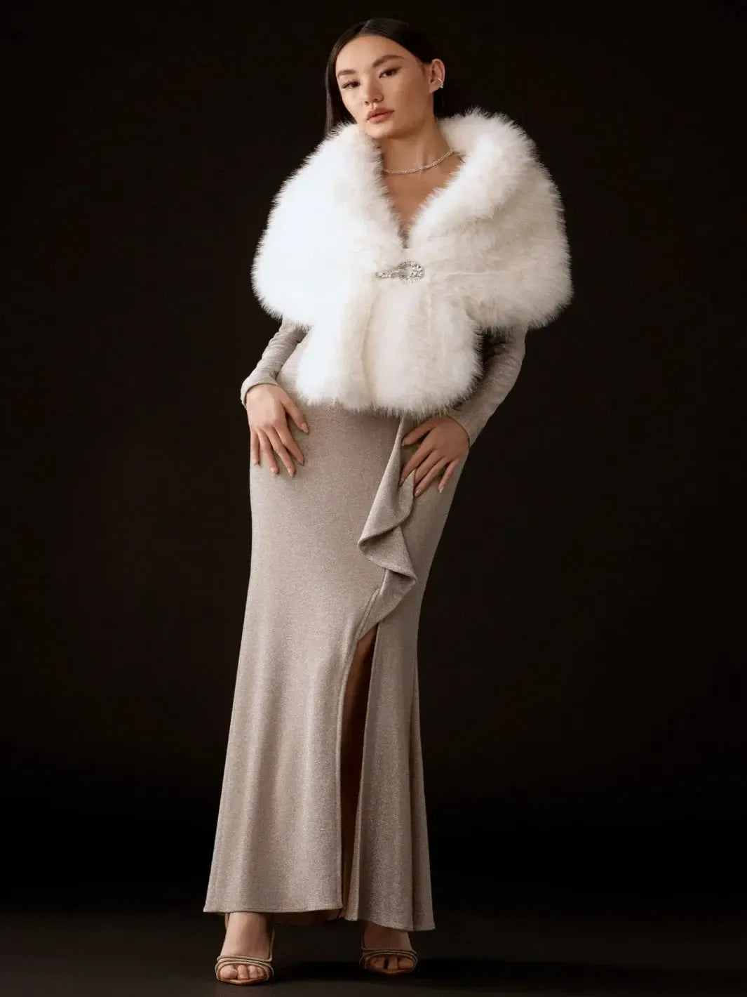 Woman wearing a white fur stole over a beige dress against a black background