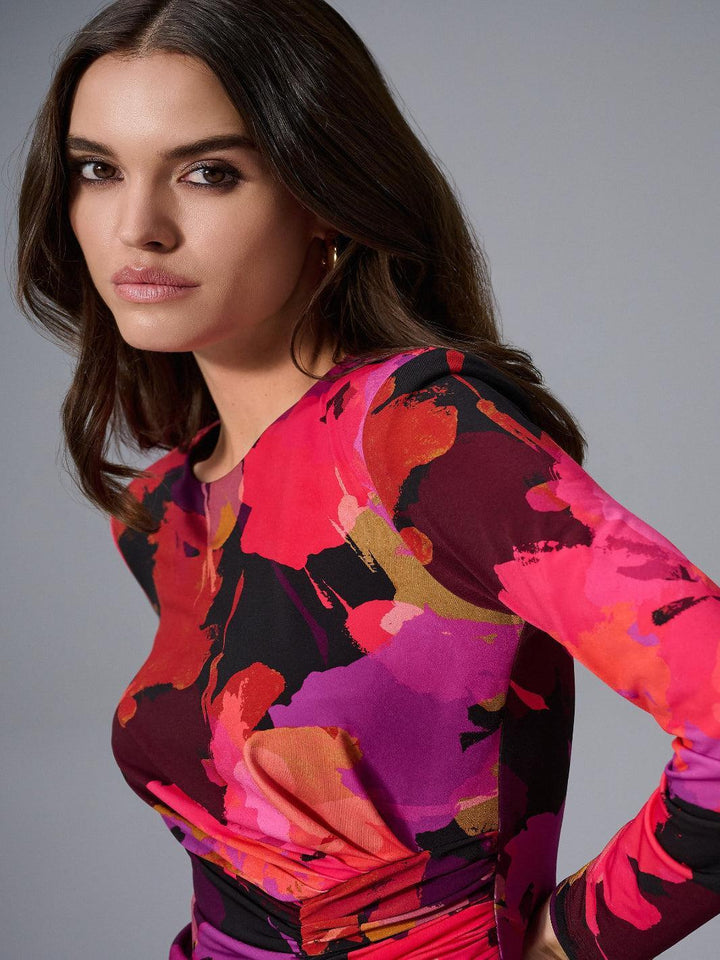 Woman wearing a colorful floral dress against a gray background