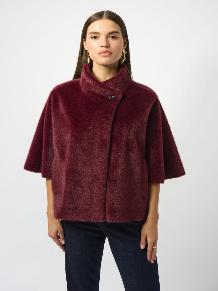 Woman wearing a burgundy cape over a plain background