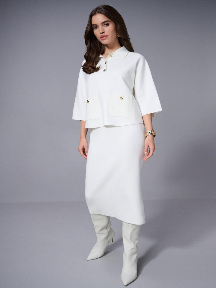 Woman wearing a white outfit with a jacket and skirt on a gray background