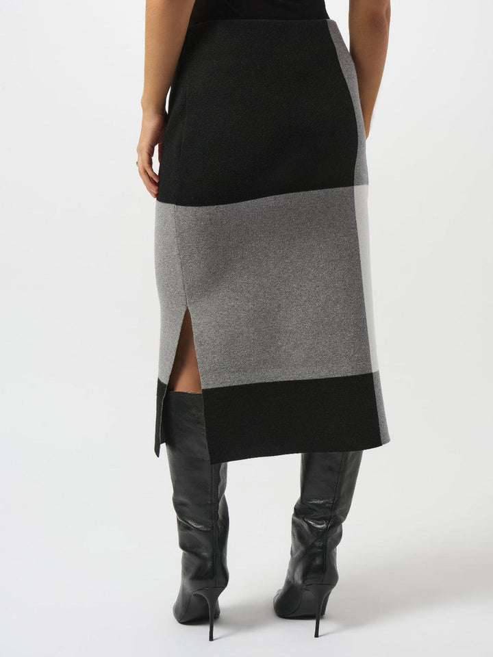 Person wearing a black and gray color-blocked skirt with high-heeled boots on a white background