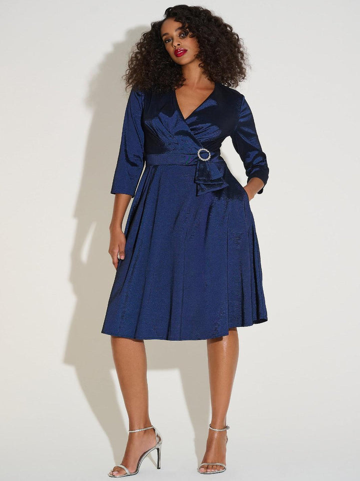 Woman wearing a blue dress with a belt against a white background