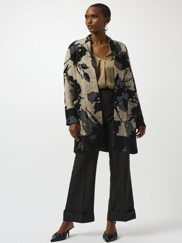 Woman wearing a floral coat and black pants on a white background