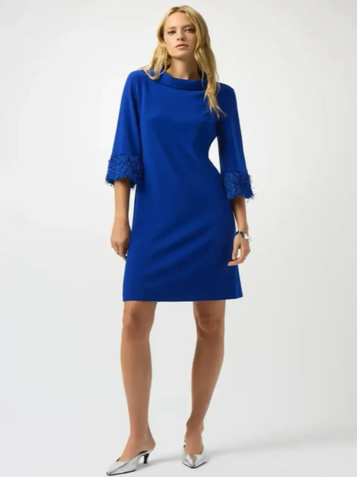 Woman wearing a blue dress with lace cuffs on a white background