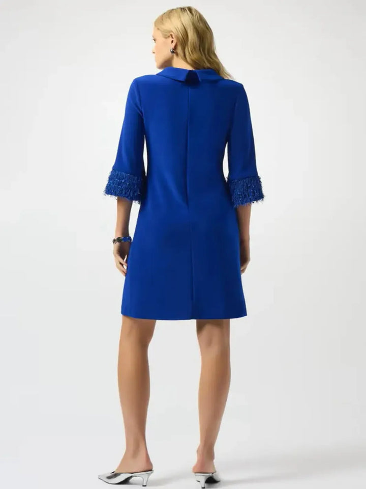 Woman wearing a blue dress with lace cuffs on a white background