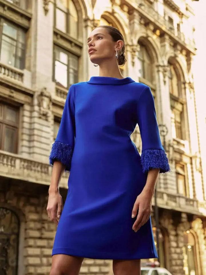 Woman wearing a blue dress with lace cuffs in an urban setting