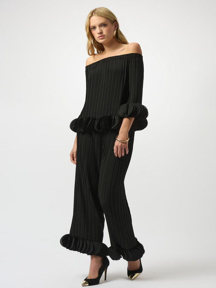 Woman wearing a black off-shoulder top and wide-leg pants on a white background