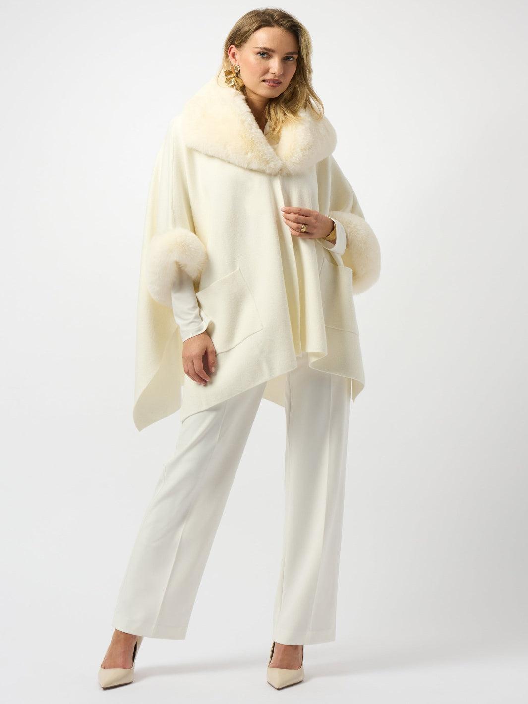 Woman wearing a cream-colored fur-trimmed poncho on a white background