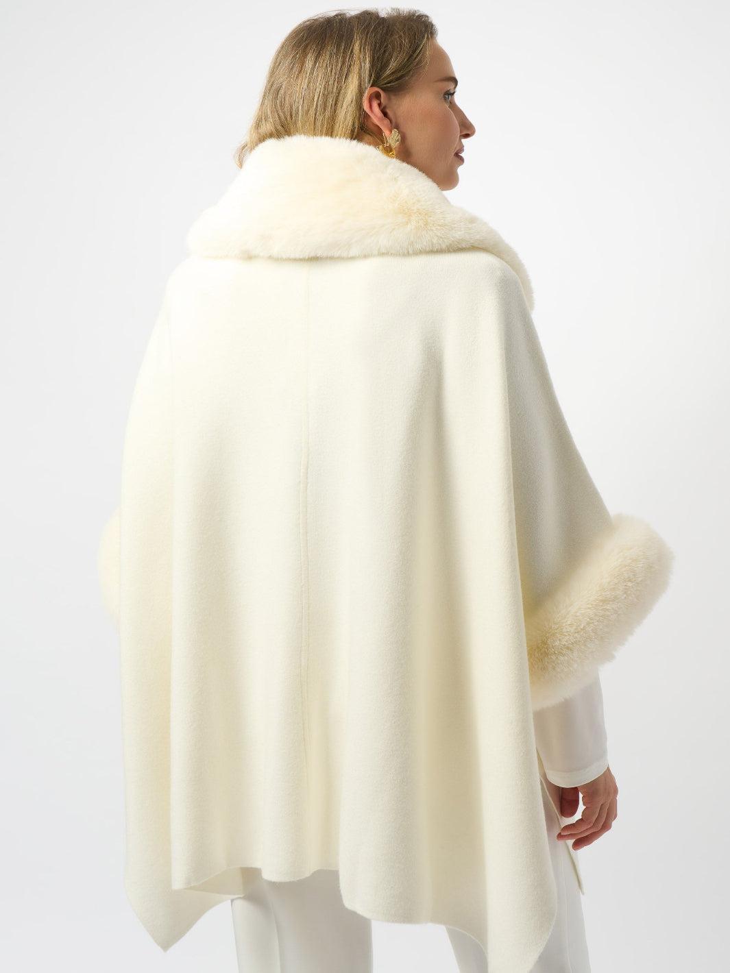 Woman wearing a cream-colored poncho with fur trim on a white background