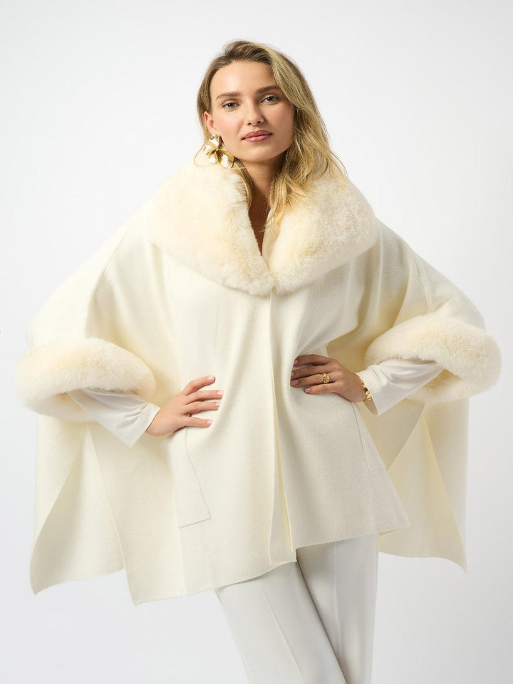 Woman wearing a cream-colored cape with fur trim on a white background