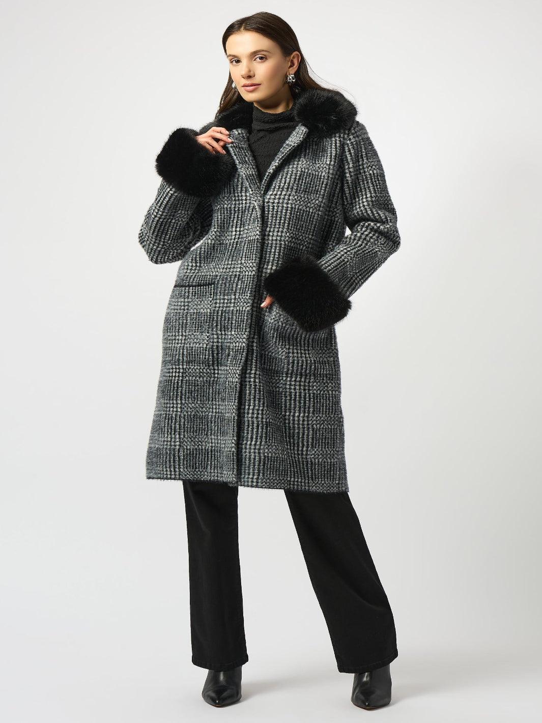 Woman wearing a checkered coat with black fur trim on a white background