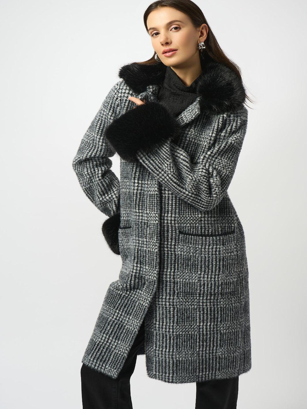 Woman wearing a long checkered coat with black fur trim on a white background