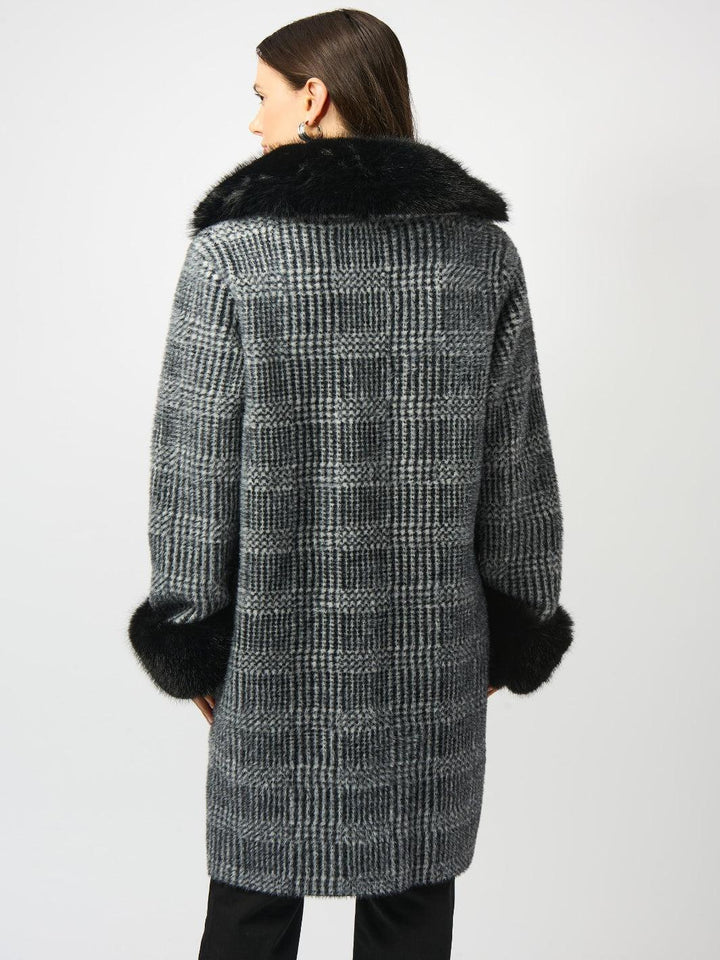 Woman wearing a checkered coat with fur trim on a white background