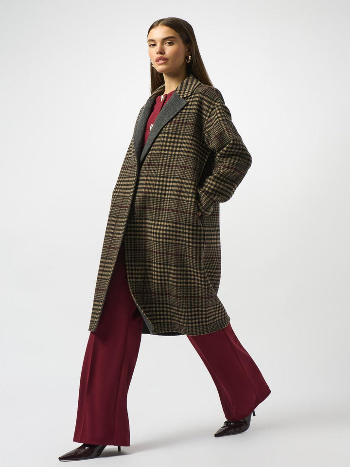 Woman wearing a plaid coat and burgundy pants on a white background