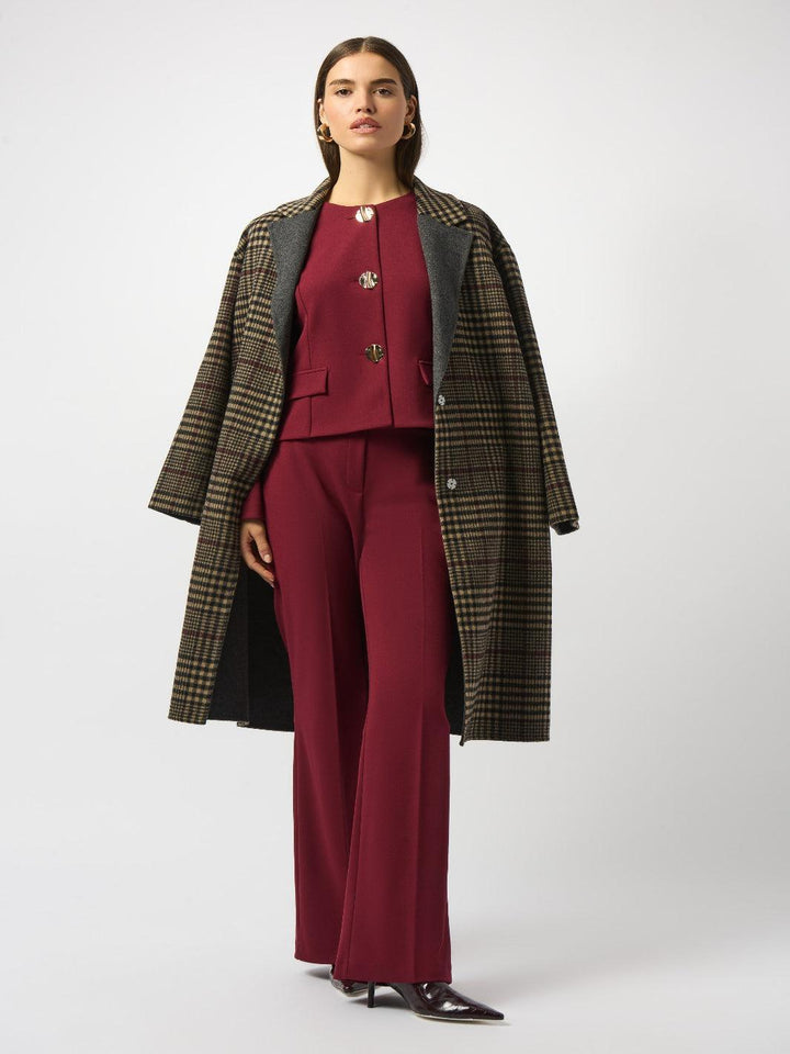 Woman wearing a red outfit with a plaid coat on a white background