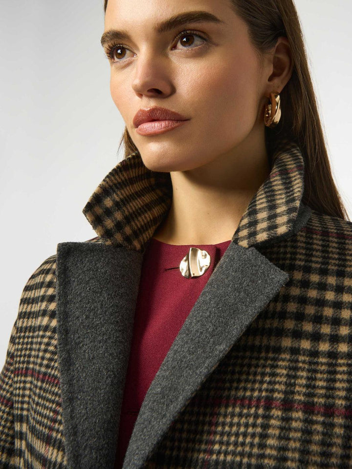 Woman wearing a checkered coat with a plain background