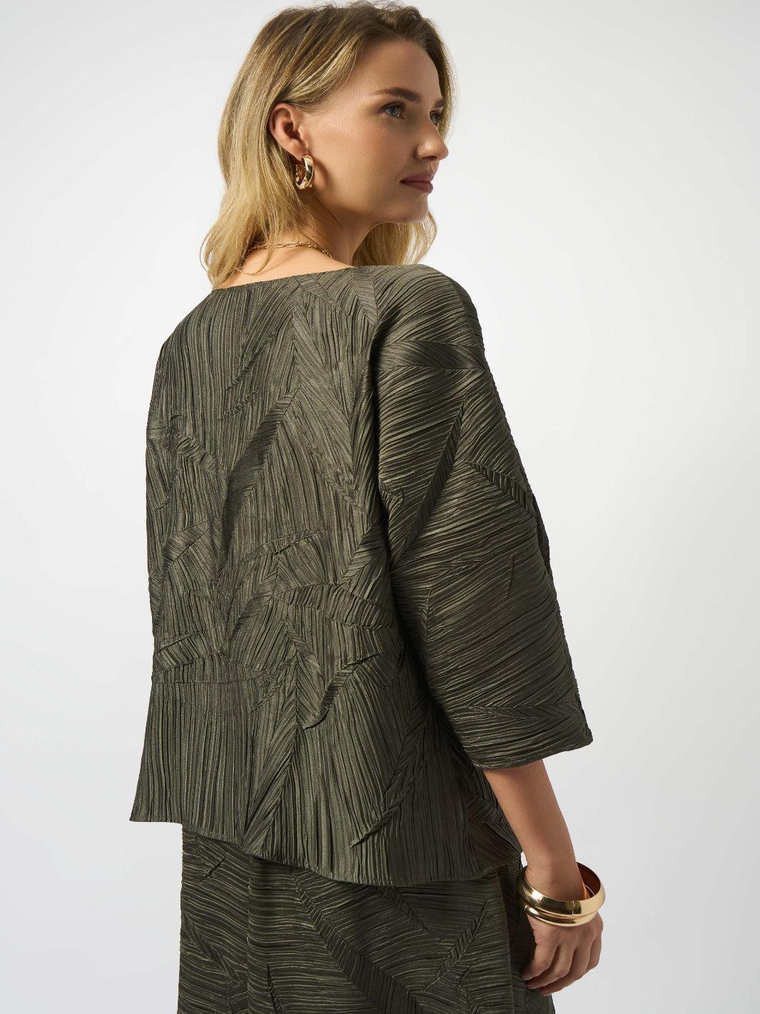 Woman wearing a green textured top and pants against a white background