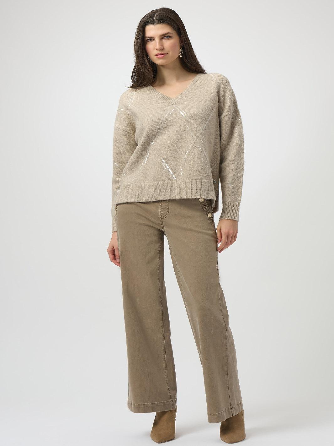 Woman wearing a beige sweater and pants on a white background