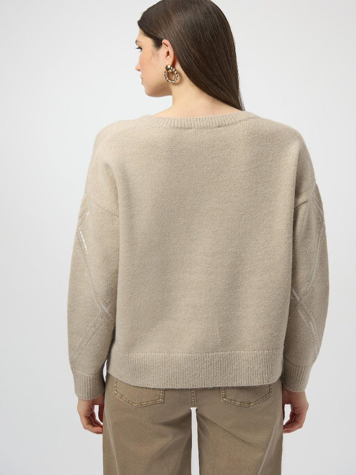 Person wearing a beige sweater and pants on a white background