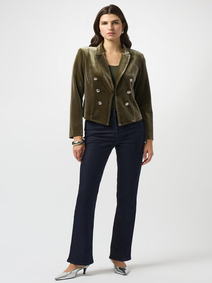 Woman wearing a green jacket and navy pants on a white background