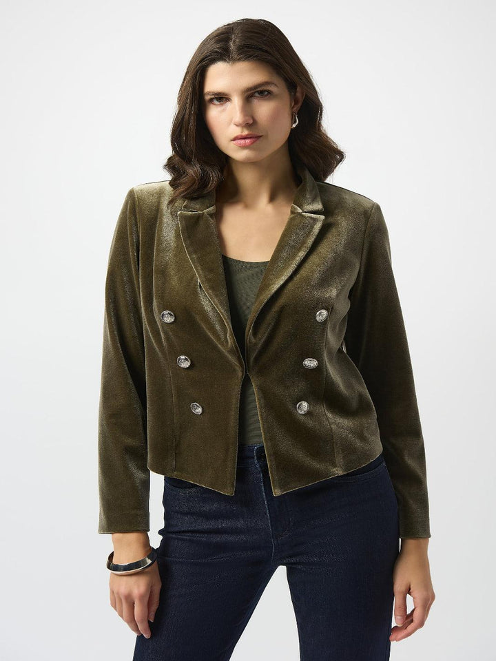 Woman wearing a green velvet blazer with white buttons on a white background
